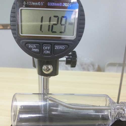Thickness gauge measuring the wall of a clear plastic bottle
